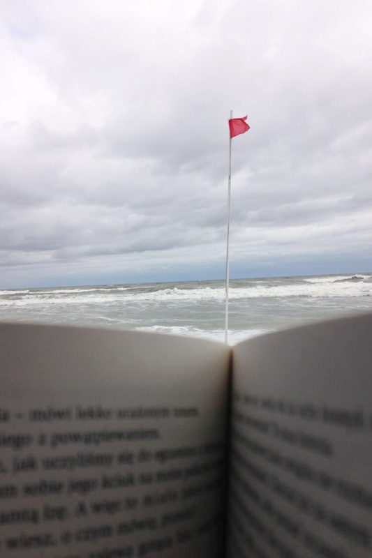 Czerwona flaga, fale, zimno i... ksiażka (widok z kosza plażowego)