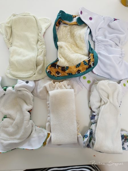 Srodek pieluszki, od lewej SIO, potem otulacz z wkładem, kieszonka, drugi rząd to AIO, obok druga AIO i trzecia też AIO, a jednak każda ciut inna